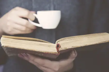 Buch mit Kaffee im stehen lesen.